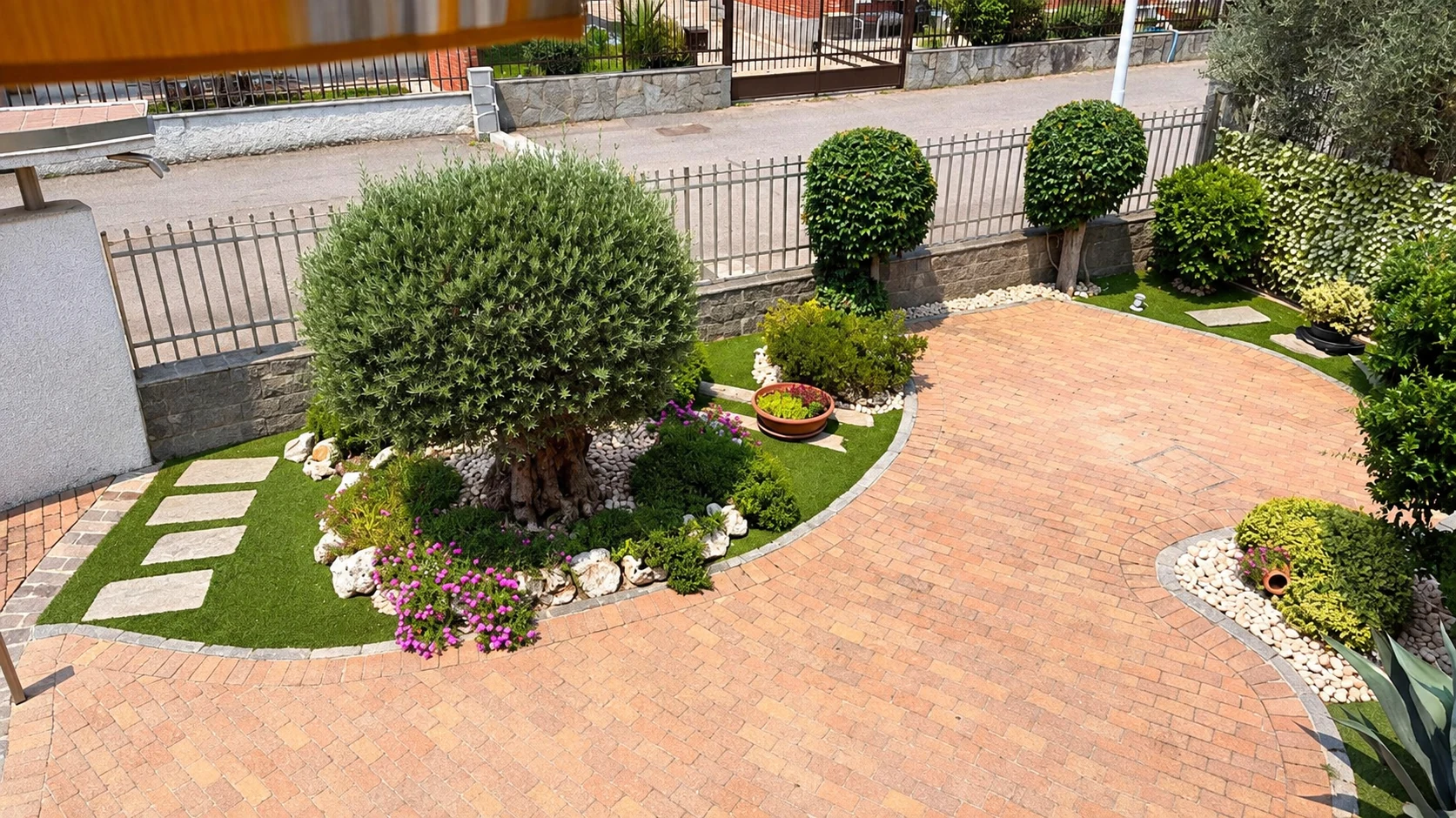 Aiuole con ulivo, bordure e verde in un cortile residenziale &mdash; Immagine illustrativa elaborata con AI